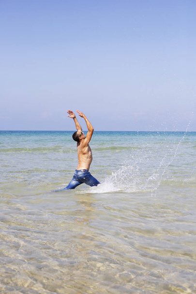 young muscular man posing and splashing around in the sea - Fotó, kép