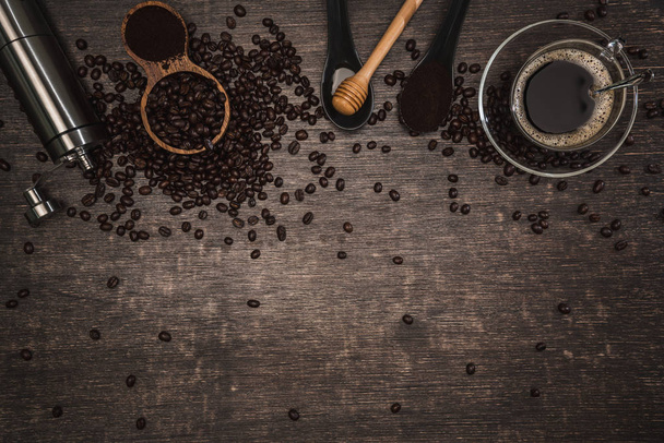 茶色のコーヒー豆と蜂蜜と木製のテーブルの上に置かれたホットコーヒーのカップ.木の背景とエスプレッソと豆。テキストのコピースペースのトップビュー. - 写真・画像