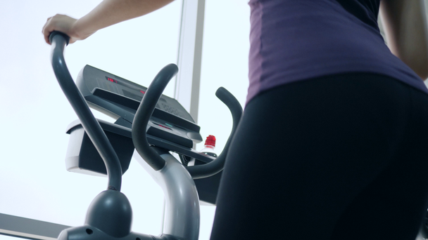 beautiful figure, ass female in black leggings on sports simulator in gym close-up - Materiaali, video