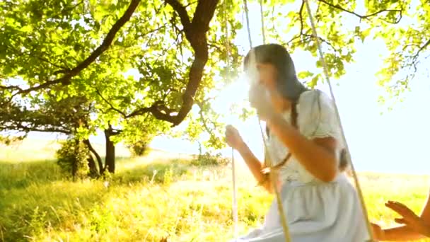 Dziewczyny z długimi włosami huśtawka na biegunach i uśmiechając się szczęśliwie pod drzewem Dąb letni. Zwolnionym tempie. - Materiał filmowy, wideo