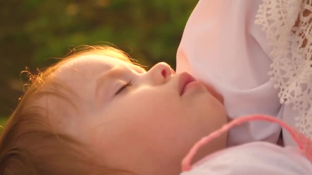 Malé děťátko spí na máminých rukou v záři zapadajícího slunce. Silueta máma houpající se dítě v náručí. Mateřská láska a péče - Záběry, video
