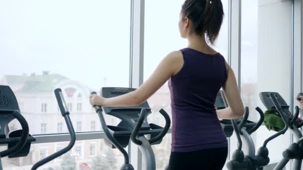 心臓トレーニング魅力的な女性はパノラマの窓のあるジムでスポーツ用具の練習をします - 映像、動画