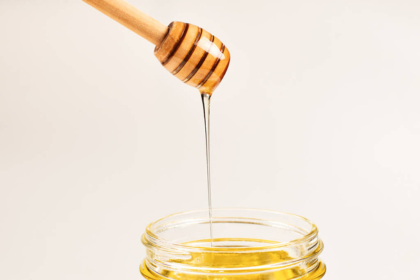 Dipper met honing in de hand van een vrouw. Ruimte voor tekst of ontwerp.  - Foto, afbeelding
