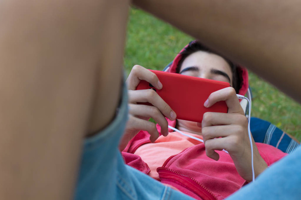 close-up de jovem com telefone celular e fones de ouvido no campo relaxado
 - Foto, Imagem