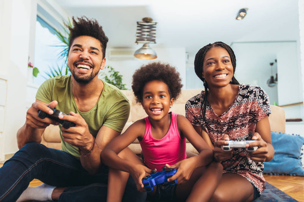 家族がビデオ ゲームを一緒にソファに座って笑顔 - 写真・画像