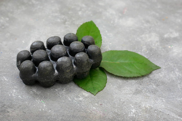 Black charcoal volcanic soap and herbal leaves red rose petals on grey background. Put your text. - Foto, Bild
