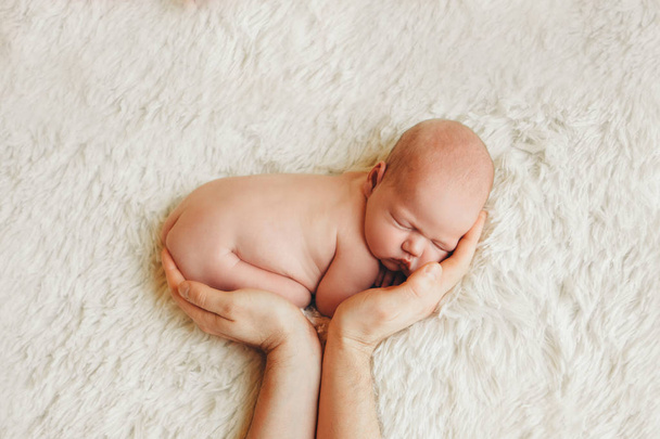 naked newborn baby lying on the hands of parents on a white background. Imitation of a baby in the womb. beautiful little girl sleeping lying on her stomach. - Fotoğraf, Görsel