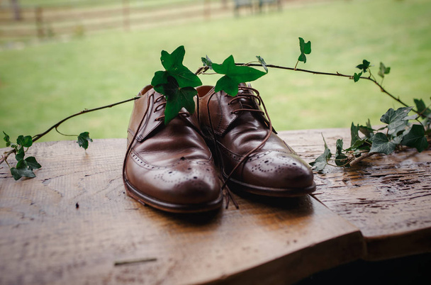 Belles chaussures de marié marron élégant sur une table en bois avec branche de lierre
 - Photo, image