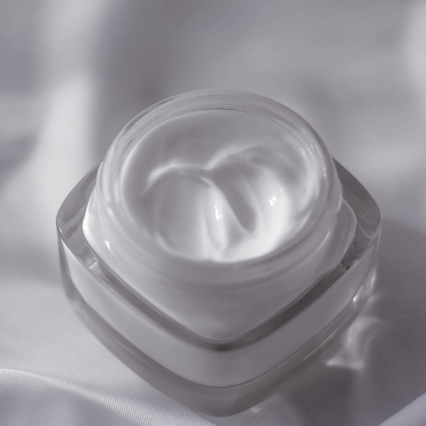 Face cream moisturizer jar on silk background, moisturizing skin - Foto, imagen