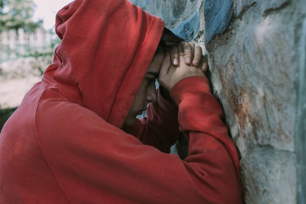 portrét mladého muže s kapucí opřenou o zeď - Fotografie, Obrázek