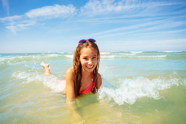 Beautiful little girl lay in the sea waves enjoying warm water on summer vacations - Photo, Image