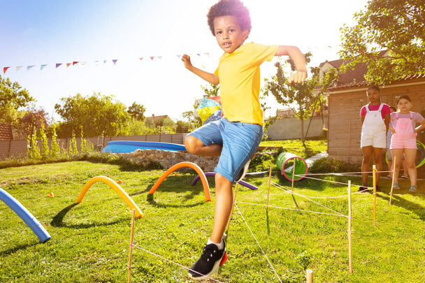 Happy boy skoków w ciągu ciągu przeszkód gry na placu zabaw w grupie dzieci - Zdjęcie, obraz