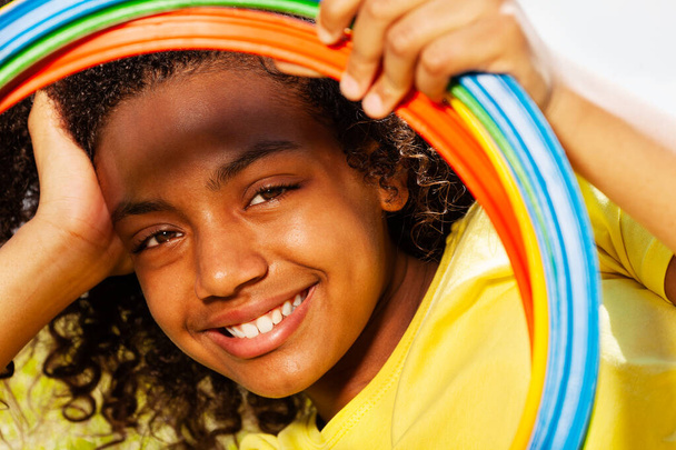 Porträt der schönen lächelnden jungen schwarzen Mischlingshündin, die durch farbige Ringe blickt - Foto, Bild