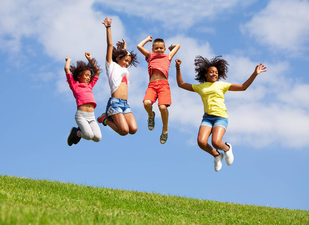 Group of divers children friends jump high over clean blue sky waving and lifting hands - Foto, Imagen