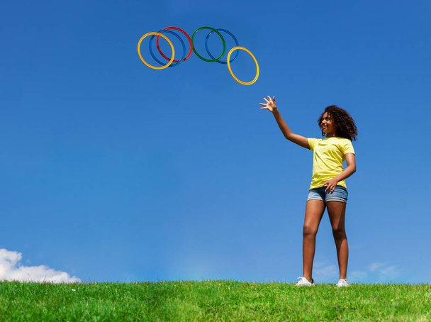Young beautiful curly hair black girl throwing hoops in the air over clean sky background - Φωτογραφία, εικόνα