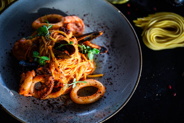 tuoretta italialaista pastaa - spagettia äyriäisten ja tuoreiden vihannesten ja mausteiden kanssa
 - Valokuva, kuva