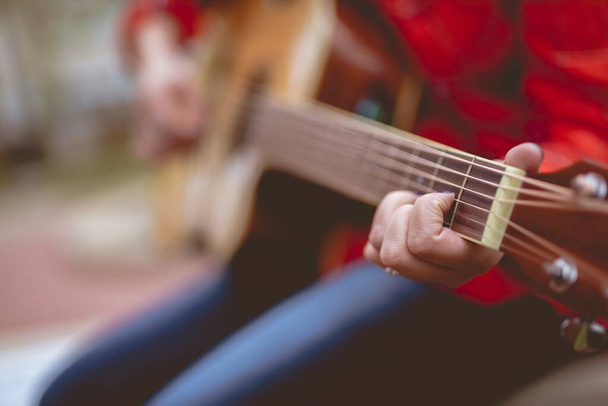 Closeup shot of a female playing the guitar with a blurred background - 写真・画像