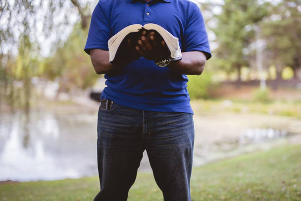 Hombre de pie y leyendo la biblia con un fondo borroso
 - Foto, Imagen