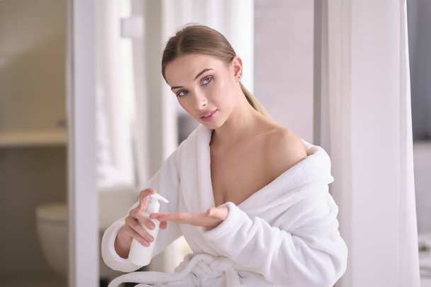 Young woman with flawless skin, applying moisturizing cream on h - Фото, изображение
