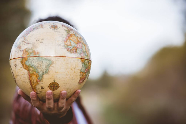 Closeup shot of a person holding a globe with a blurred background - Zdjęcie, obraz