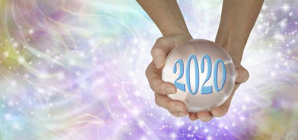 Τι Θαύματα Θα 2020 Φέρτε για σας Banner - θηλυκά χέρια κρατώντας μεγάλη σαφή κρυστάλλινη σφαίρα δείχνει 2020 σε ένα αφρώδες αιθέριο πολύχρωμο φόντο με αντίγραφο χώρο - Φωτογραφία, εικόνα