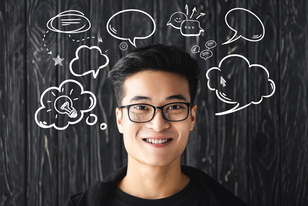 lächelnder asiatischer Mann mit Brille blickt in die Kamera auf Holzgrund mit Illustration   - Foto, Bild