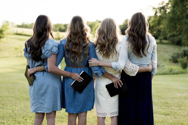 Beautiful shot of four girls with their arms around each other while holding the bible - 写真・画像