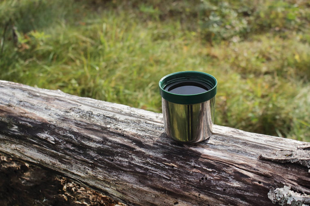 Thermos green plastic stainless steel mug on a log - Photo, Image