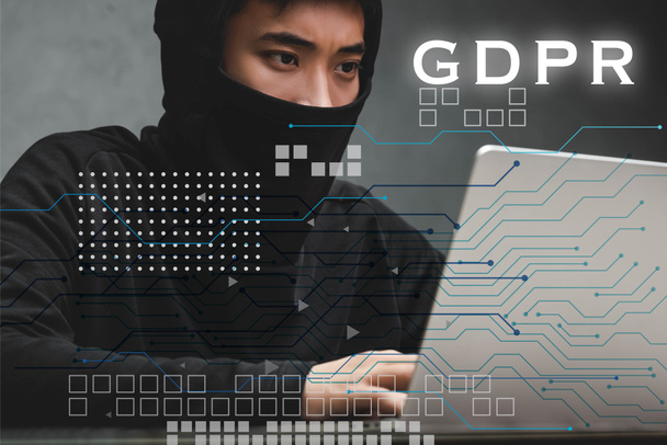 hacker asiático usando el ordenador portátil y sentado cerca de ilustración gdpr
  - Foto, imagen