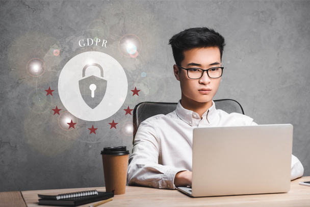 asian businessman using laptop and sitting near padlock illustration and gdpr lettering  - Photo, Image