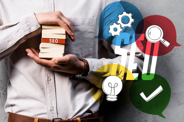 cropped view of seo manager holding wooden rectangles and standing near seo illustration - Photo, Image