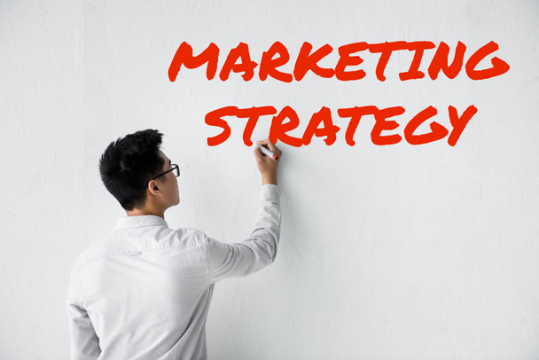 назад вид Seo Менеджер пишет на стене с иллюстрацией маркетинговой стратегии
 - Фото, изображение