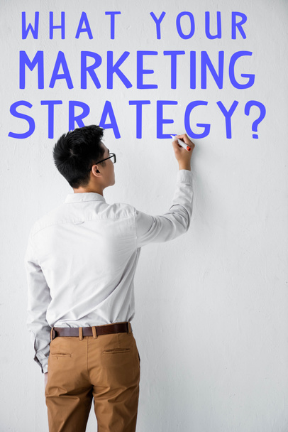 back view of seo manager writing on wall with what your marketing strategy illustration  - Photo, Image