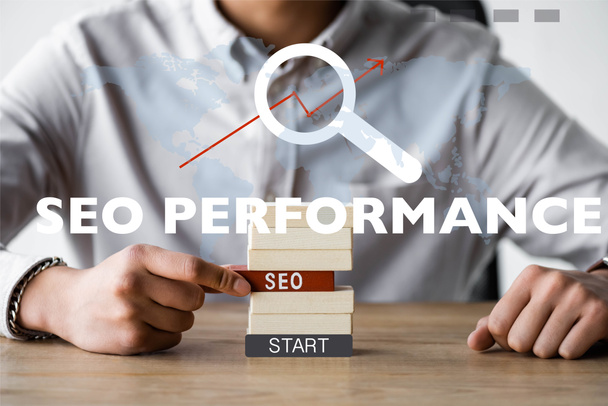 cropped view of seo manager holding rectangle with seo lettering and sitting near seo performance illustration  - Foto, afbeelding