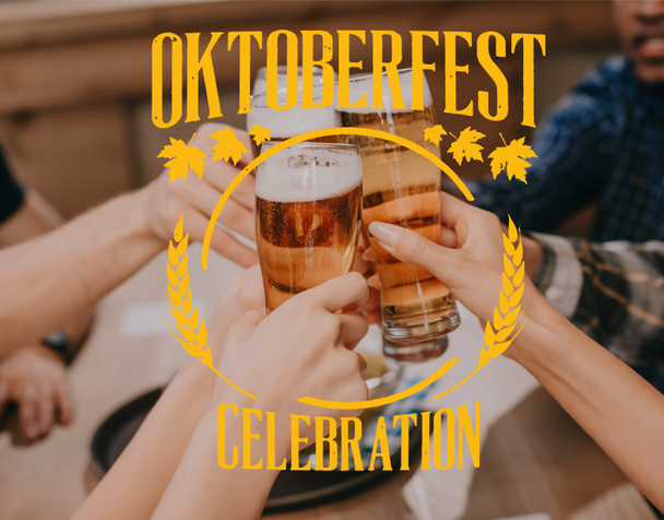 cropped view of multicultural friends clinking glasses with beer in pub with Oktoberfest celebration illustration - Zdjęcie, obraz