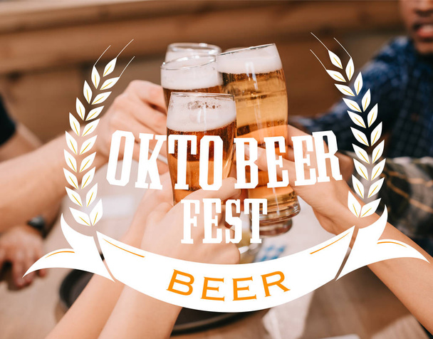 cropped view of multicultural friends clinking glasses with beer in pub with Oktobeer fest illustration - Фото, зображення