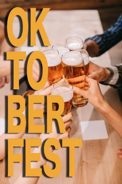 vue recadrée d'amis multiculturels cliquetis verres à bière dans un pub avec illustration Oktoberfest
 - Photo, image