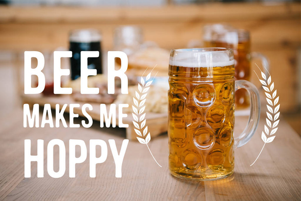 selective focus of mug with lager beer on wooden table near beer makes me hoppy illustration - Foto, Imagem