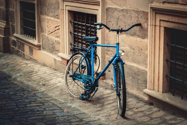 Small blue bicycle standing next to a building - Zdjęcie, obraz