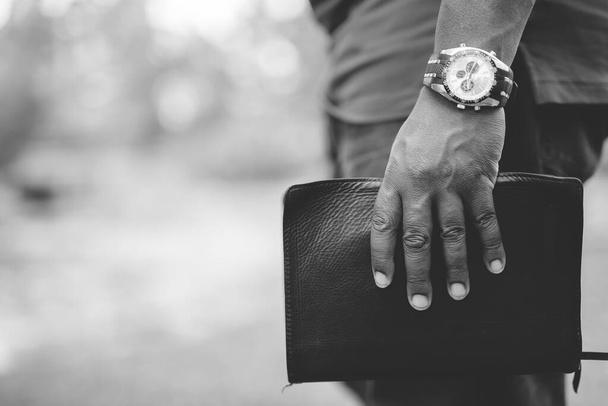 Closeup shot of a male holding the bible with a blurred background in black and white - Fotoğraf, Görsel