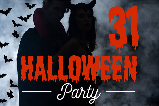 silhouette of couple in costumes standing on black with smoke and Halloween party lettering - Photo, Image