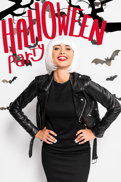 houkutteleva nainen valkoisessa peruukissa hymyilee ja katselee kameraa lähellä punaista Halloween-puolueen kirjoitusta
 - Valokuva, kuva