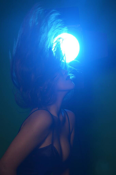 A vertical shot of a female flipping her hair in a light - Photo, Image