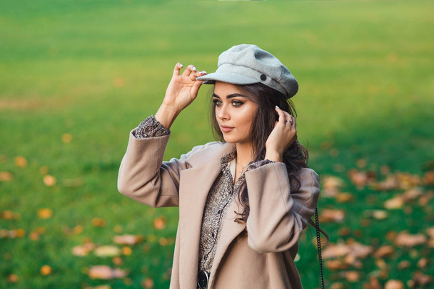 Gorgeous beautiful fashion woman in autumn park. Fashion portrait of beautiful girl with luxury makeup, long curly hair in stylish outfit - 写真・画像