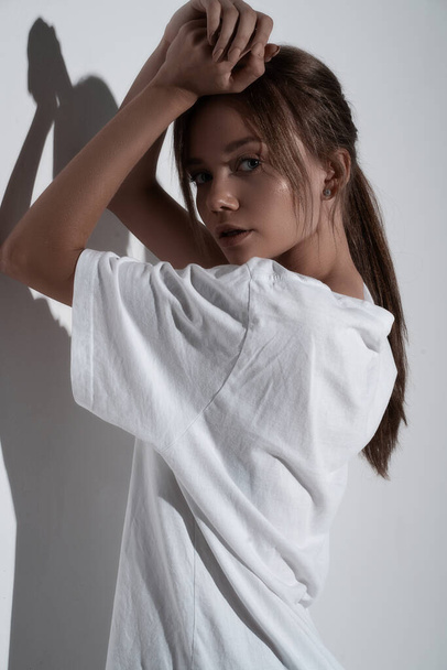 Όμορφη νεαρή σαγηνευτική γυναίκα που ποζάρει στο δωμάτιο σε λευκό φόντο. Μόδα glamour σέξι κορίτσι μοντέλο σε πουκάμισο και εσώρουχα. Κομψό πορτραίτο - Φωτογραφία, εικόνα