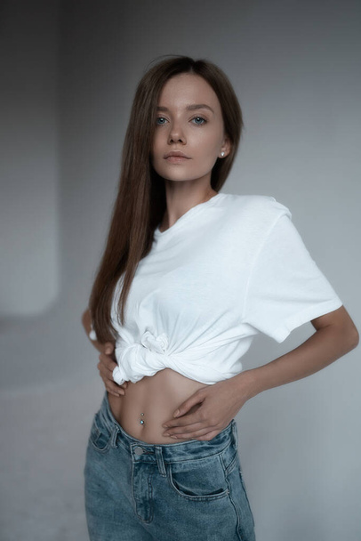 Πορτρέτο του κομψό ελκυστικό κορίτσι σε πουκάμισο και τζιν. Σέξι γυναίκα μόδας μοντέλο ποζάρουν σε λευκό φόντο στο στούντιο - Φωτογραφία, εικόνα