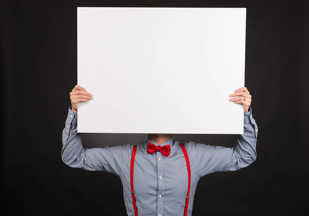 Person in blue shirt and red bow tie holding up a white plate. - Photo, Image