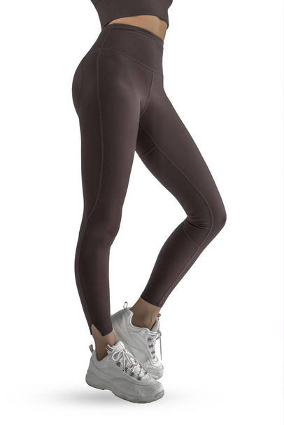 Pernas femininas finas bonitas em leggings de esporte marrom e tênis de corrida isolados no fundo branco. Conceito de roupas elegantes, esportes, beleza, moda e pernas finas
 - Foto, Imagem
