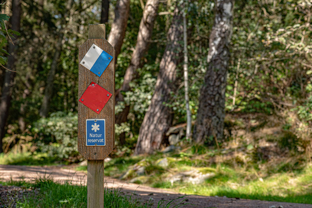 Schwedisches Schild mit der Aufschrift naturreservat, also Naturschutzgebiet. Wald im Hintergrund. - Foto, Bild