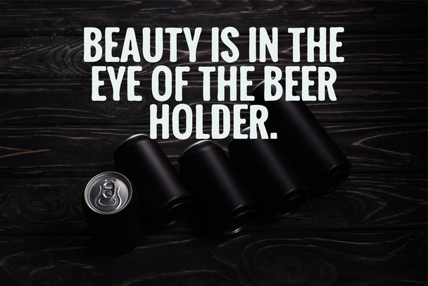black aluminum cans of beer on wooden table with beauty is in the eye of the beer holder illustration - Foto, afbeelding